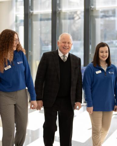 A man walks between two women in a building interior.