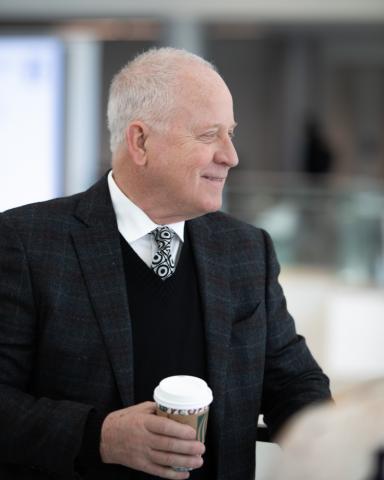 A man in business attire holding a coffee cup.